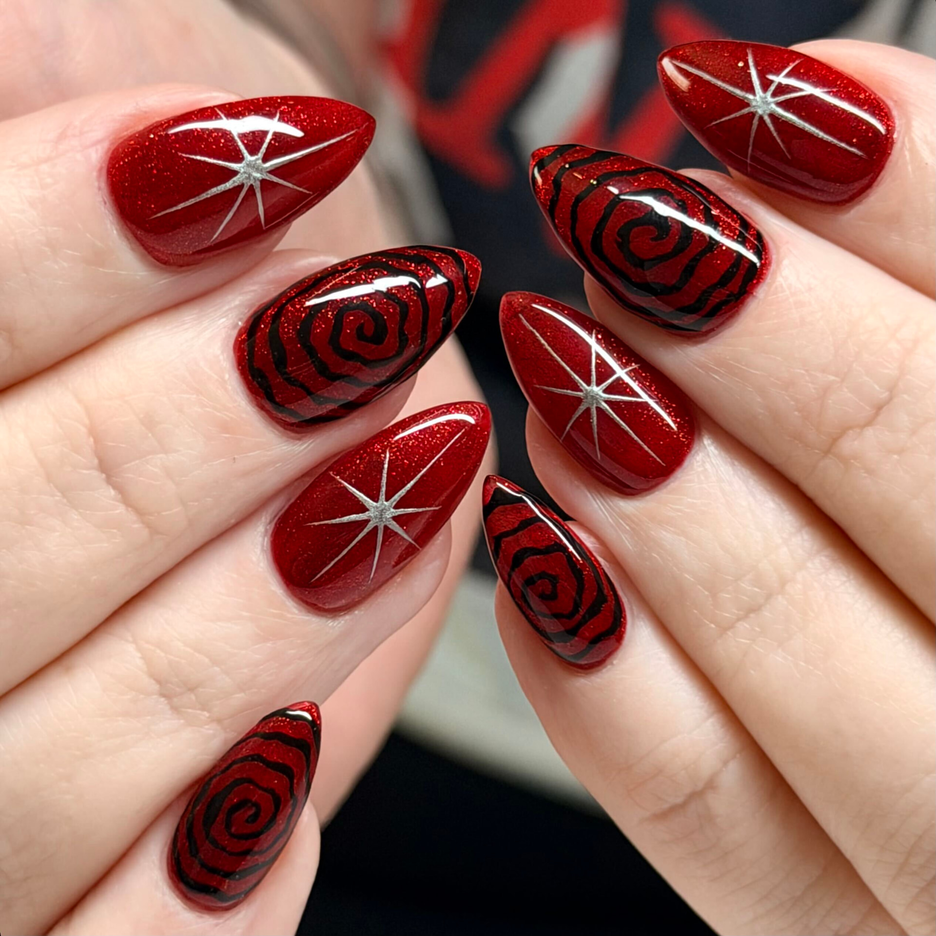 Red chrome nails with hand-painted black roses and silver starbursts
