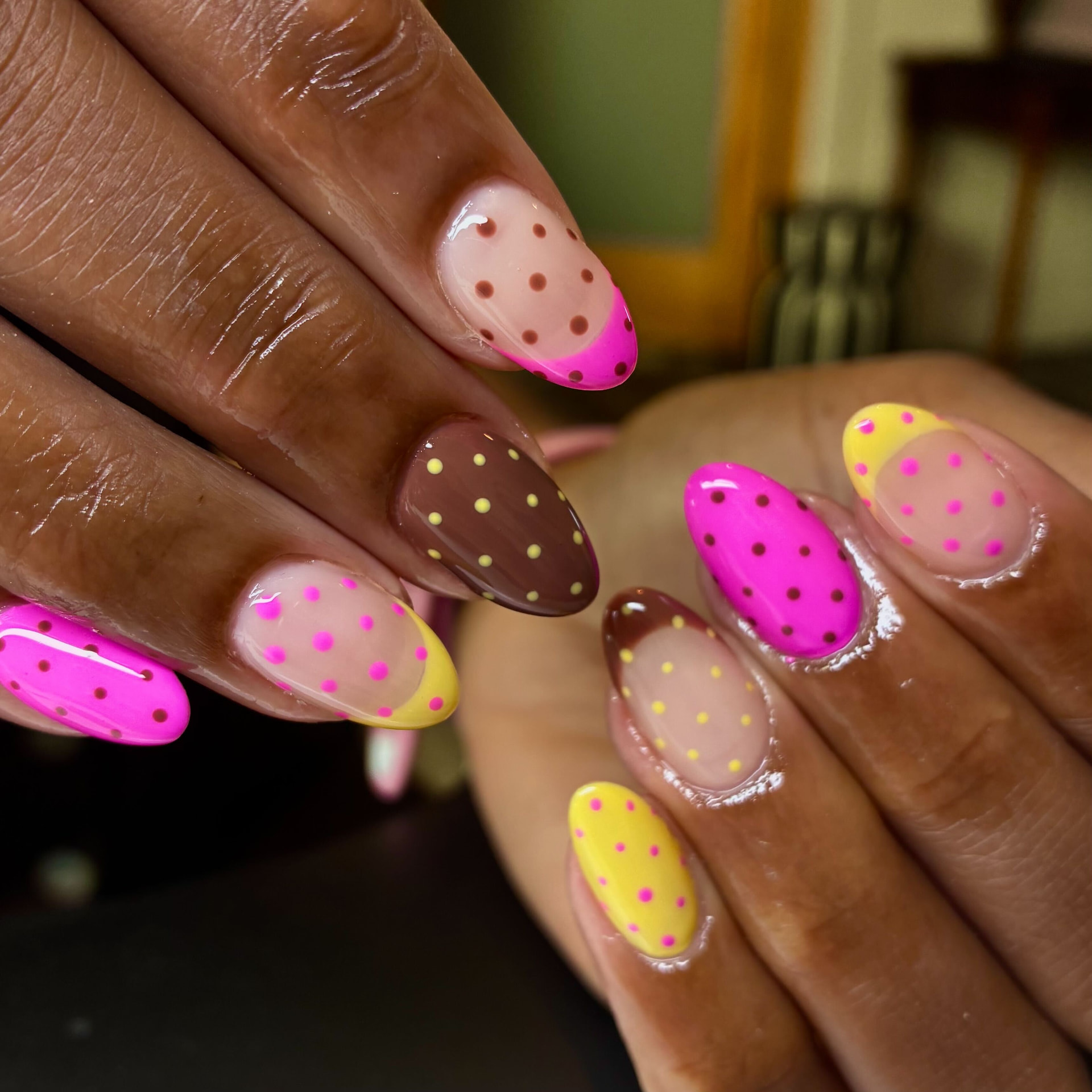 Almond nails in hot pink, brown and yellow with hand-painted polka dots and negative space tips