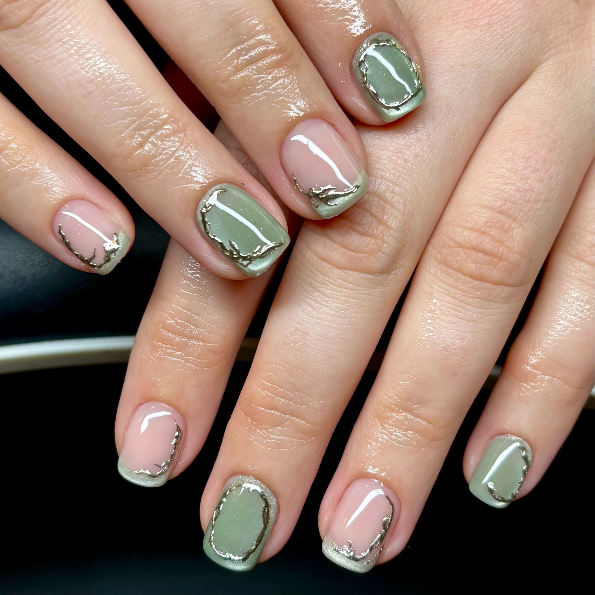 Short square sage green and sheer pink nails with hand-painted liquid gold chrome French edges