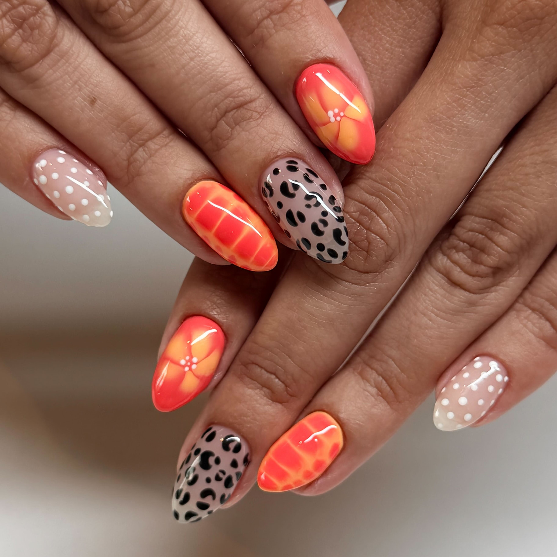 Almond nails mixing hand-painted hibiscus florals, leopard print, croc texture and white dots
