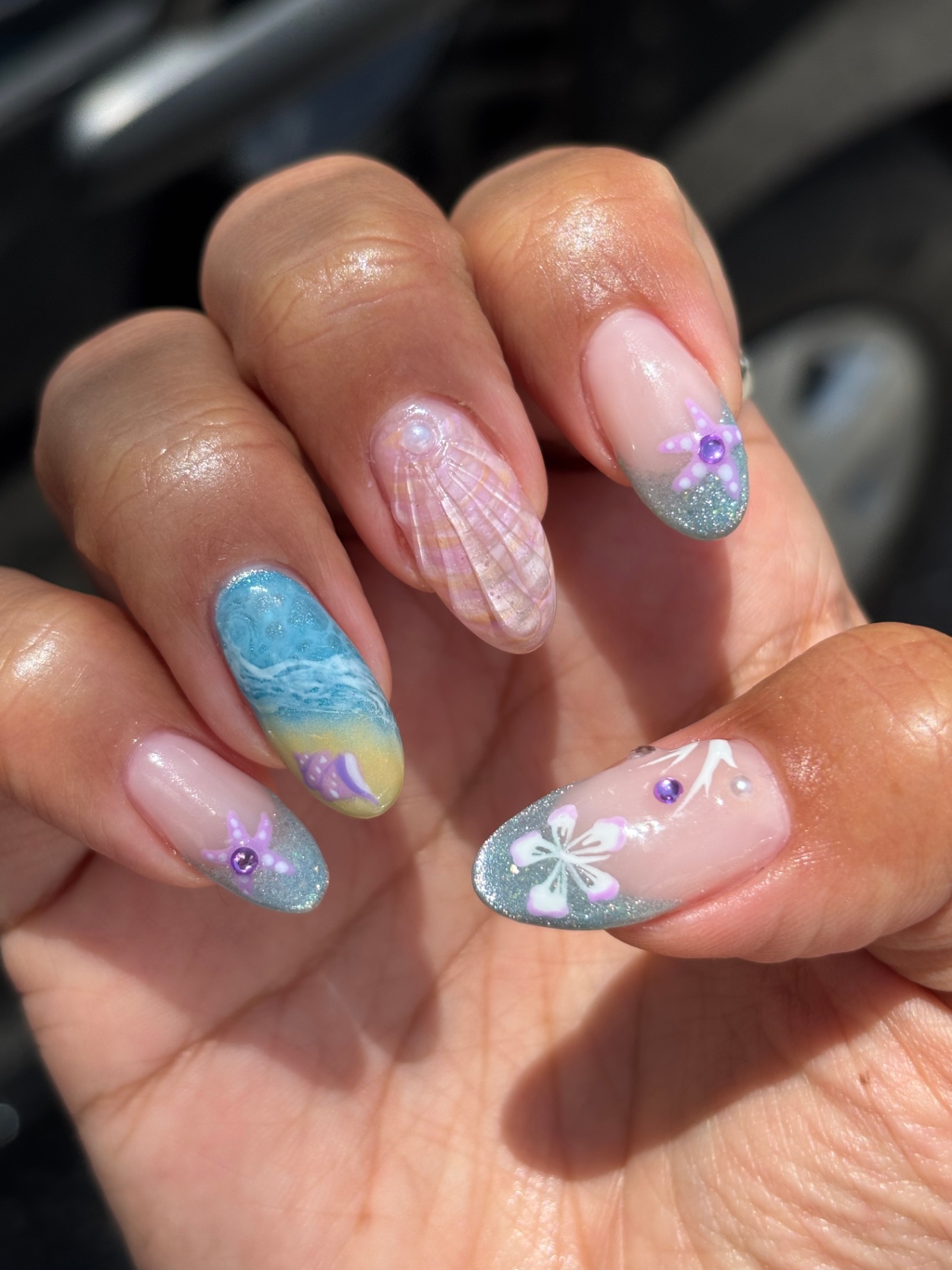 Beach-themed nails with seashells, starfish, and glitter tips