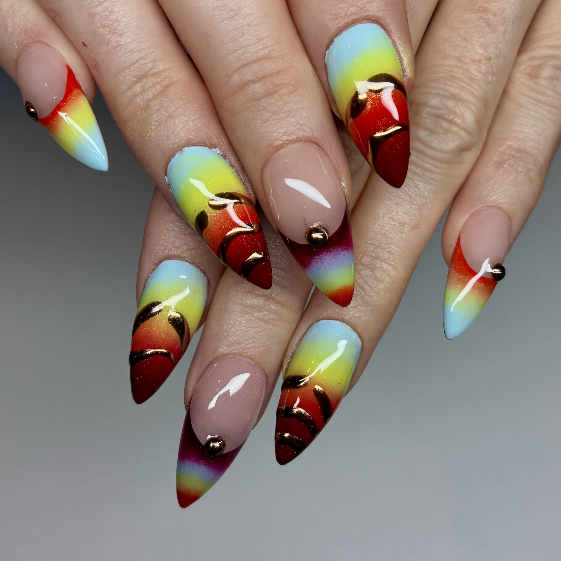 Stiletto nails with airbrushed sunset ombre and hand-painted bronze chrome swirls